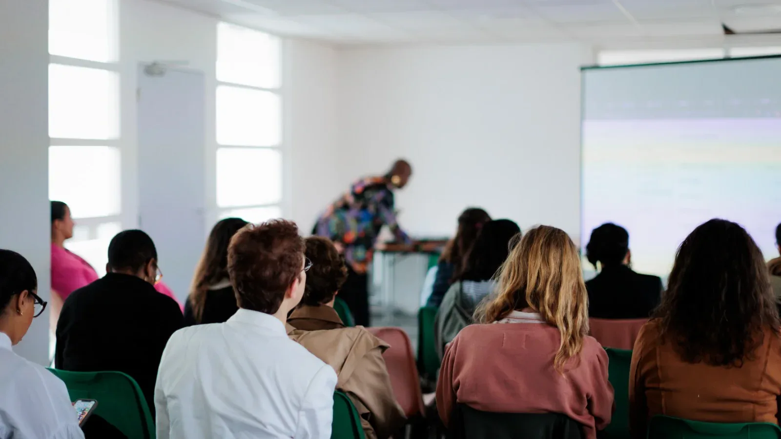 Salle de l'atelier IA des Val d'Oisiennes pendant la démo : participantes attentives, ordinateurs et téléphones sortis.
